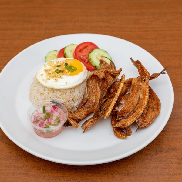 Filipino fried fish, garlic rice with fried egg, and a side of cucumber, tomato, and onion relish.