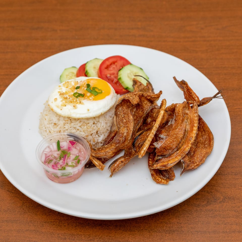 Filipino fried fish, garlic rice with fried egg, and a side of cucumber, tomato, and onion relish.